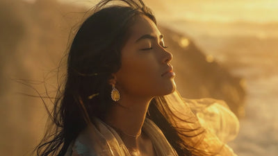 Indigenous woman standing on a coastal cliff at golden hour, wearing a handcrafted diamond ring from Shxweli’s Spirit Line